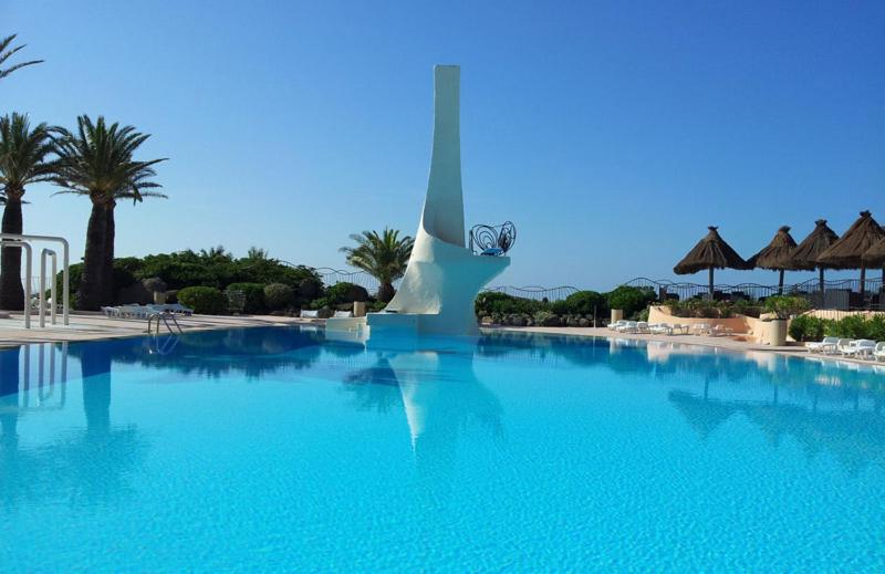 a large blue swimming pool with a statue in the background at Residence port la galere in Théoule-sur-Mer