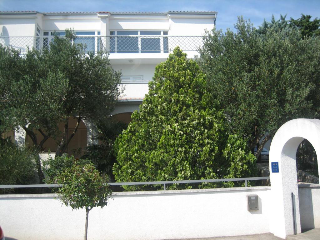 einen weißen Zaun mit Bäumen vor einem Haus in der Unterkunft Apartments G&P in Novi Vinodolski