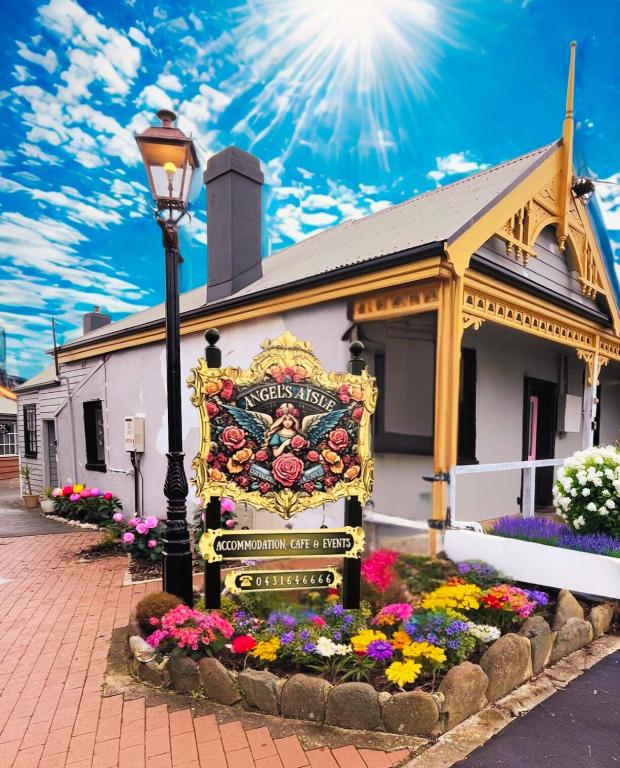 a sign in front of a building with flowers at Angel's Aisle Cottages & Cafe in Stanley