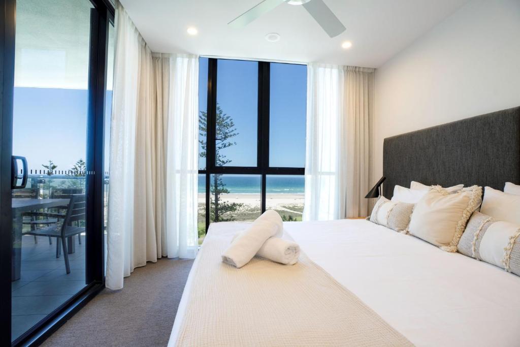 a bedroom with a white bed with a view of the ocean at Iconic Kirra Beach Resort in Gold Coast