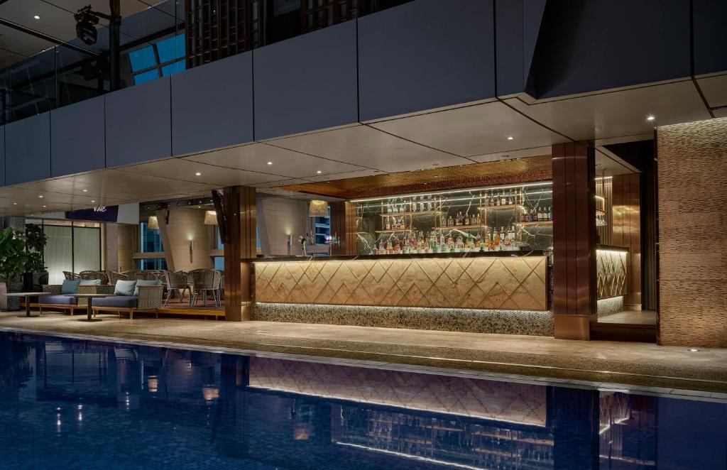 An indoor pool runs alongside a warmly lit hotel bar and lounge.