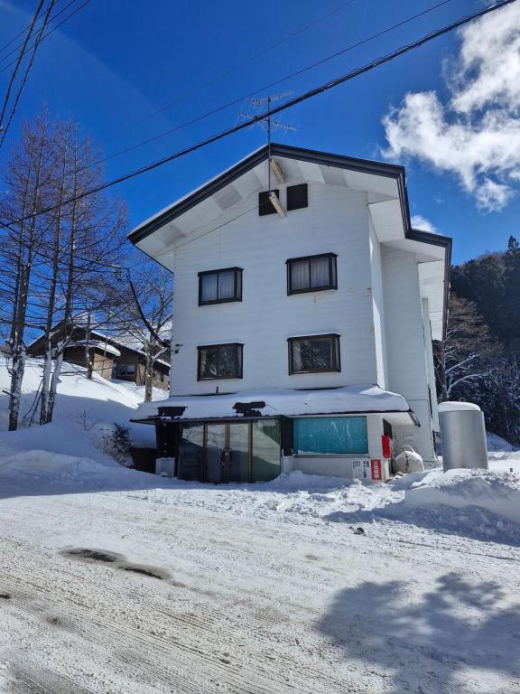 a white building with snow on the ground at Sanso On Snow in Nagano