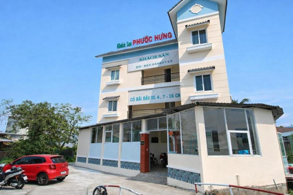 a building with a red car parked in front of it at Phước Hưng 1 Hotel in Vĩnh Long