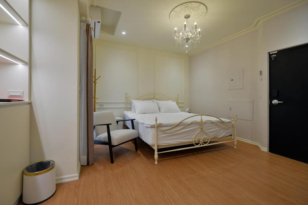 a bedroom with a bed and a chair and a chandelier at Station B&B in Tainan