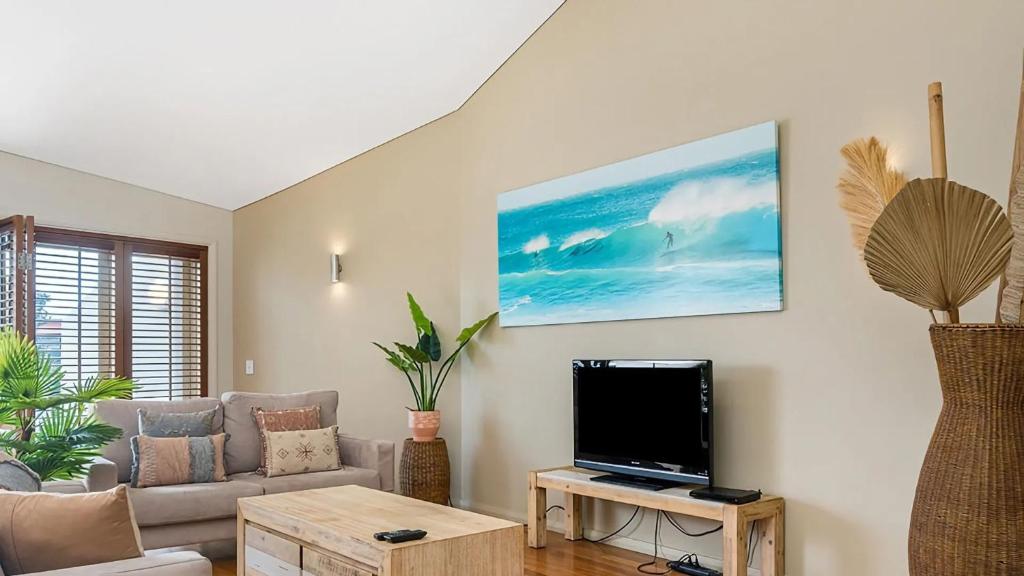 a living room with a couch and a flat screen tv at Pipi's On The Beach 1 - 2 Fletcher Street in Byron Bay