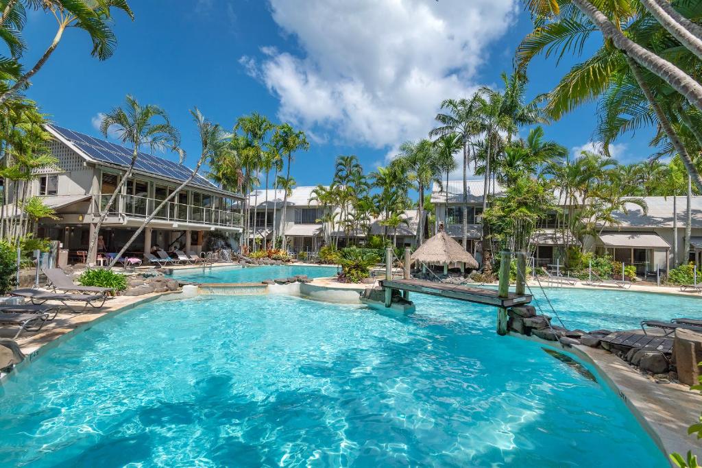 a pool at a resort with palm trees at Riverside Retreat, Noosaville in Noosaville