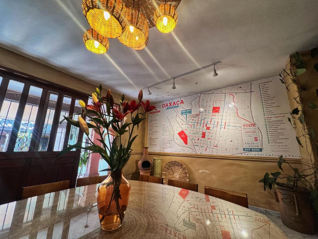 a vase of flowers on a table with a map at Hostal Central Oaxaca in Oaxaca City