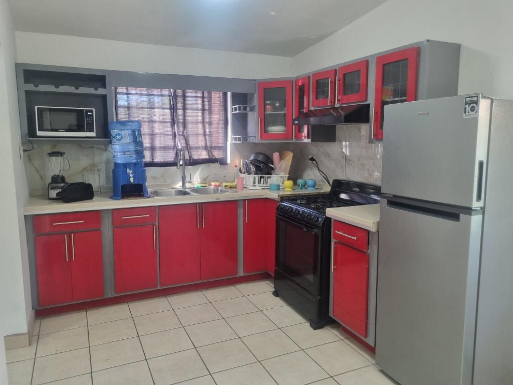 eine Küche mit roten Schränken und einem weißen Kühlschrank in der Unterkunft Libano in Manuel F. Martínez
