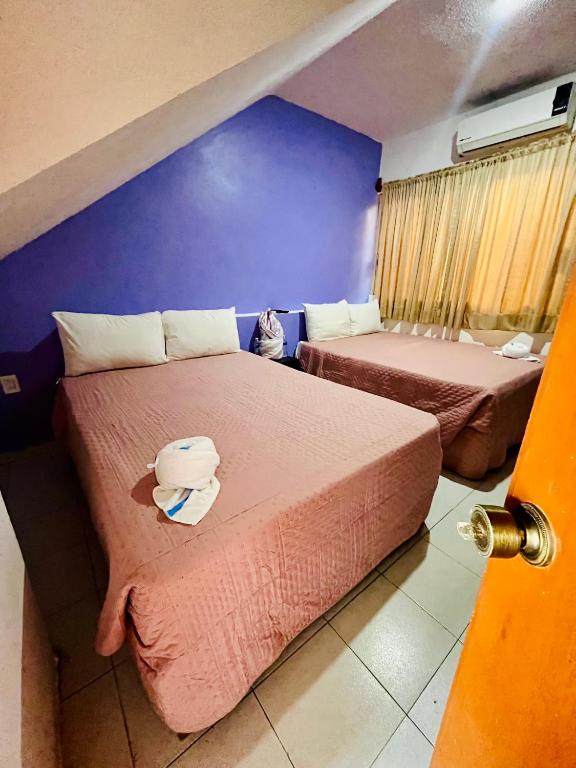 a room with two beds and a purple wall at Aibilins in Veracruz