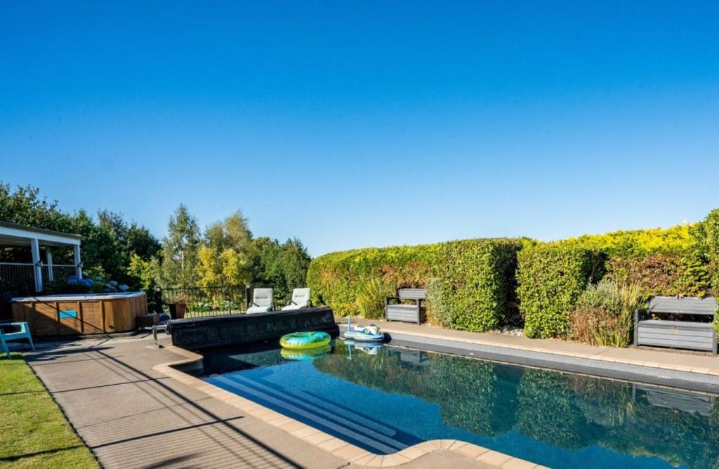 a swimming pool in a yard with a hedge at Mountviews Lodge in Taupo