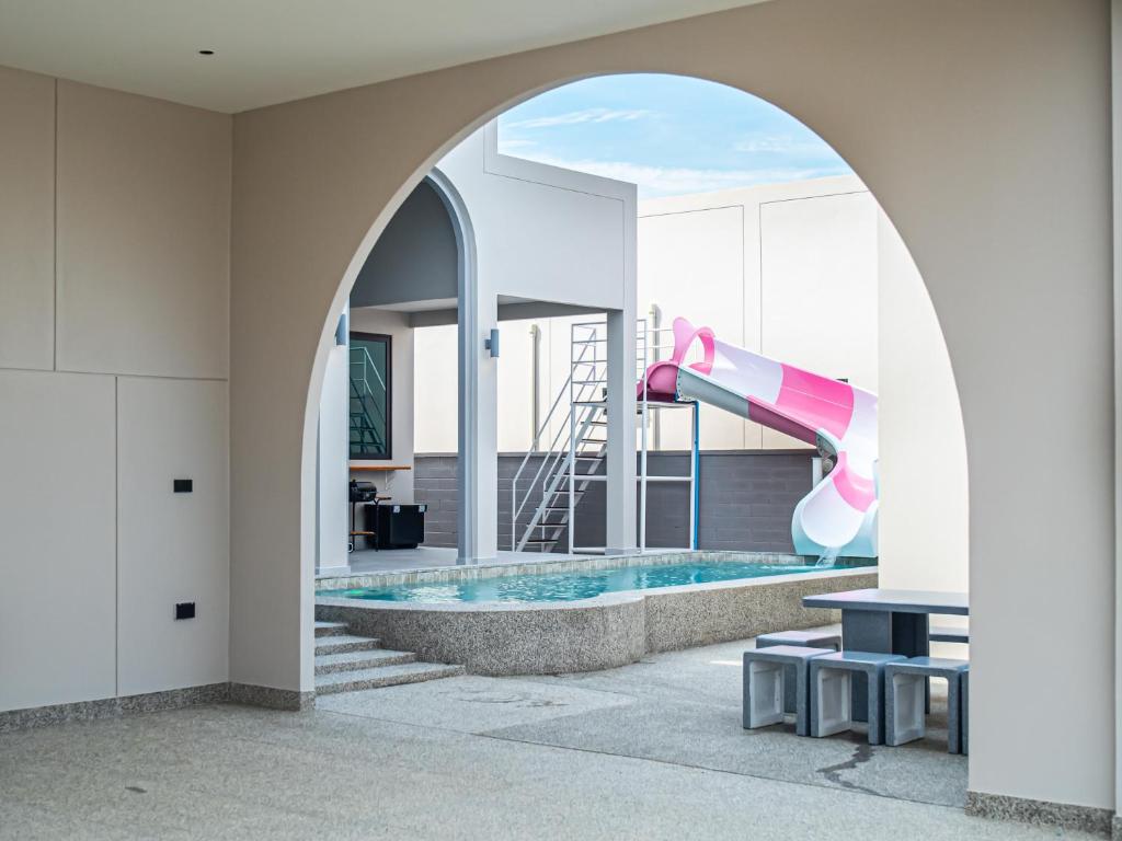 an archway leading to a pool with a water slide at Gam-Hom Poolvilla ชะอำ in Ban Hua Phrong