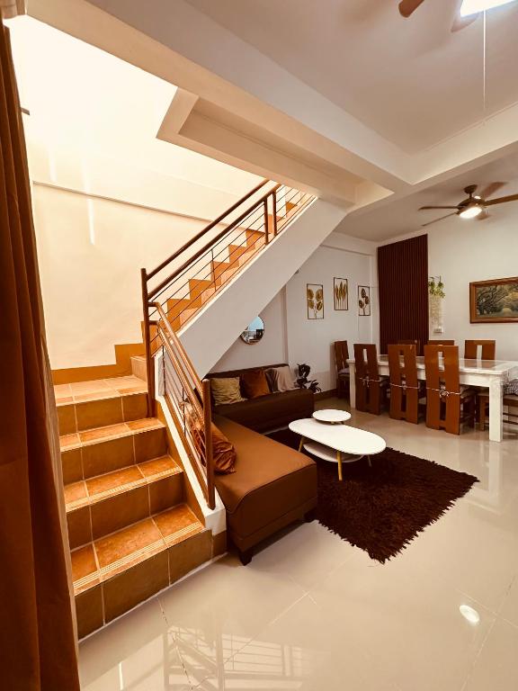 a living room with a staircase with a couch and a table at Bacolod Transient Home in Bacolod