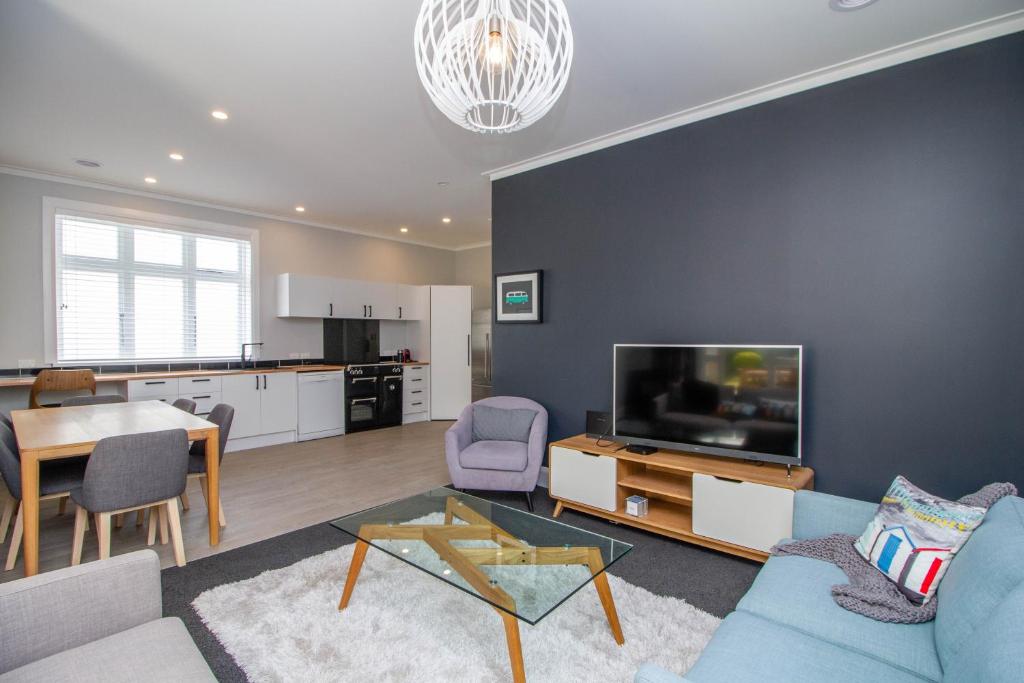 a living room with a couch and a tv and a table at Bolton Street Cottage in Lower Hutt