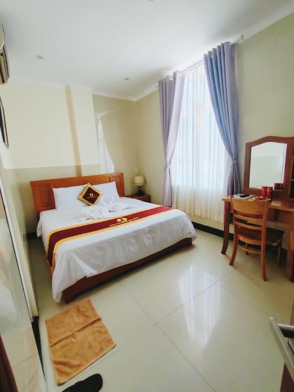 a bedroom with a bed and a table and a desk at Phú Quốc STAR hotel in Phú Quốc