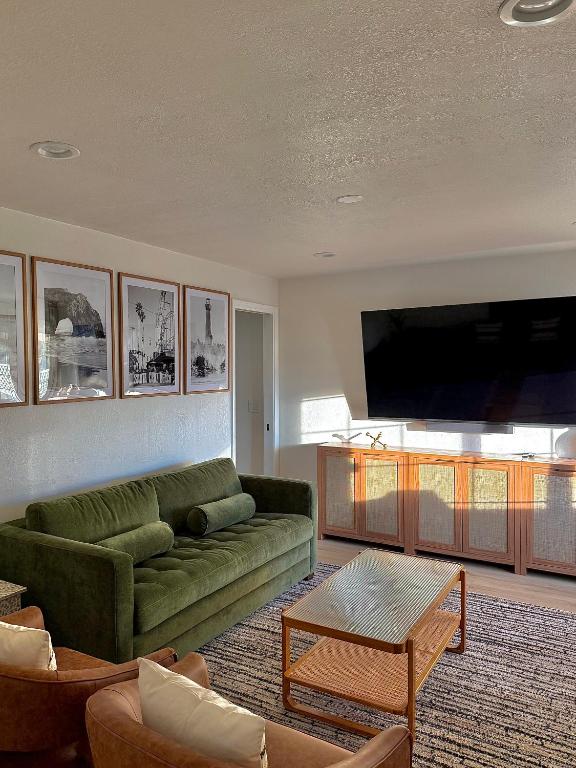 a living room with a green couch and a flat screen tv at Beach Paradise- 4 Min Walk To Beach in Santa Cruz