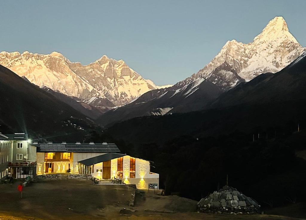 a building in front of a mountain with mountains in the background at The Himalayan Tyangboche in Thyāngboche