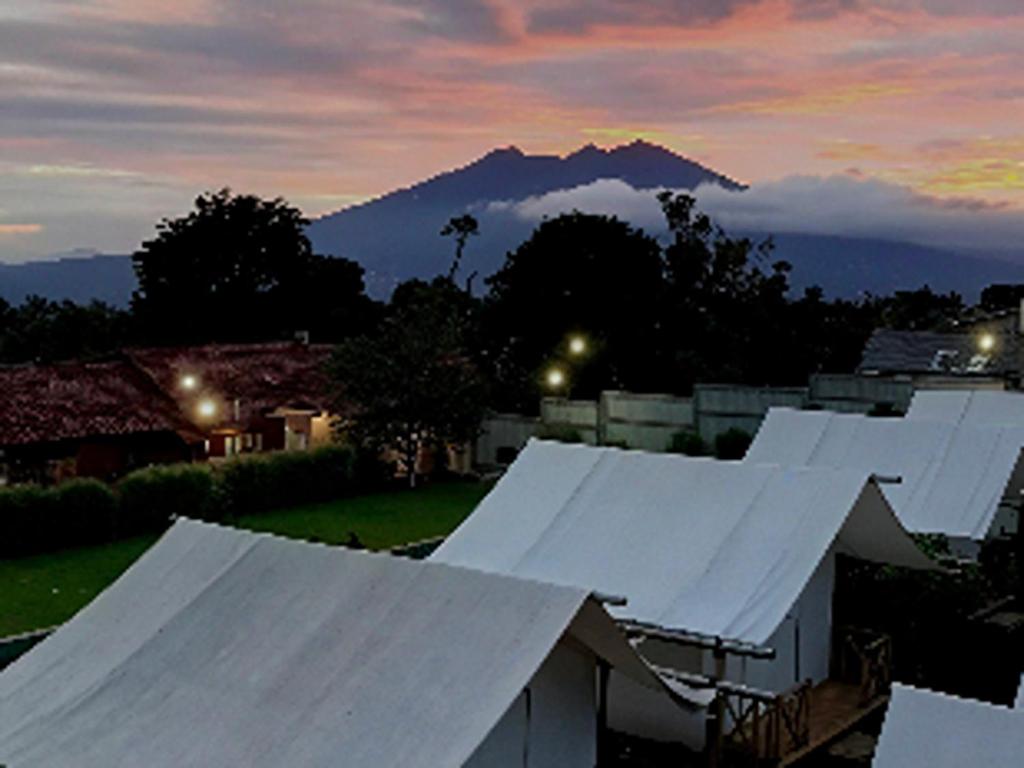 a group of white roofs with a mountain in the background at D Royale Tapos Resort Bogor in Tapos
