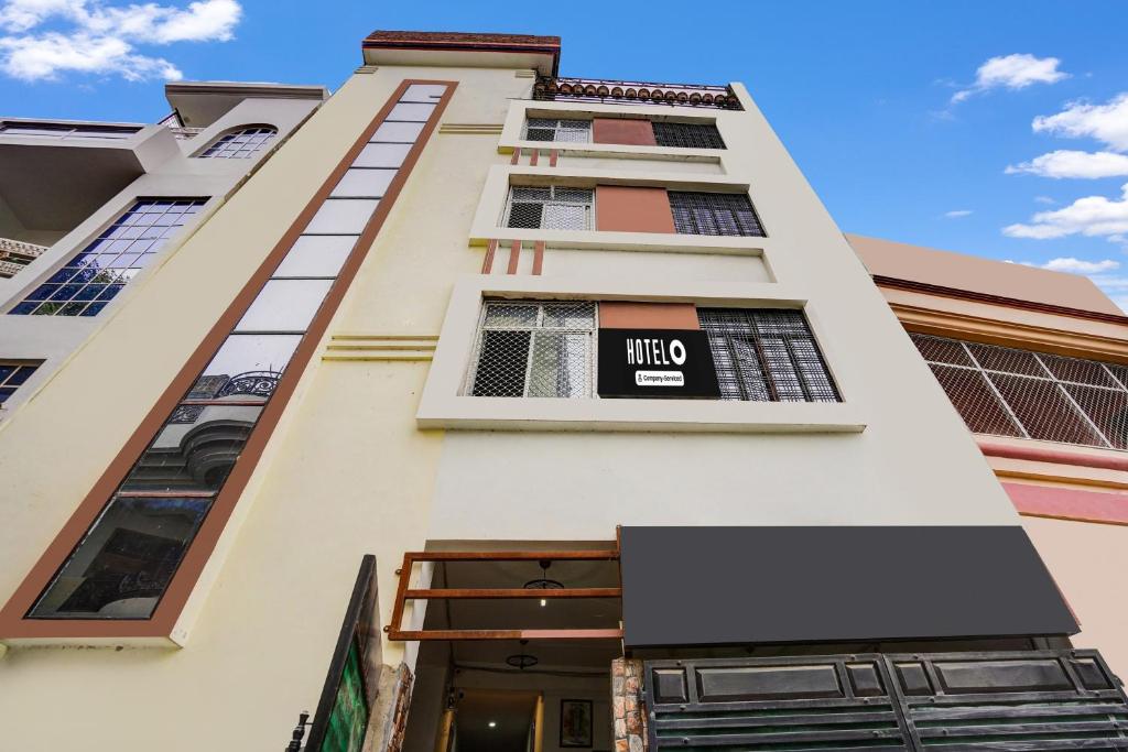 a tall white building with a sign on it at Hotel O George Town in Colonelganj