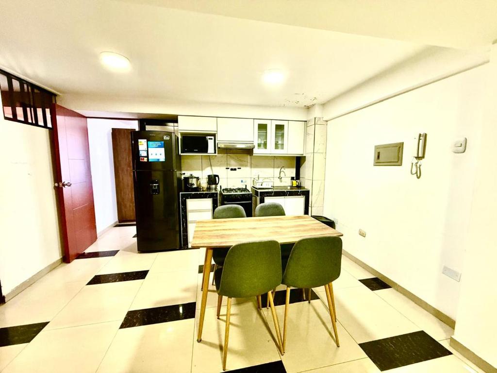 a kitchen with a wooden table and green chairs at Comfort House in Lima