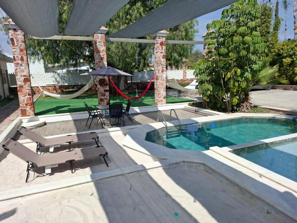 a pool with chairs and an umbrella and a hammock at Tequisquiapan Encantó in San Nicolás