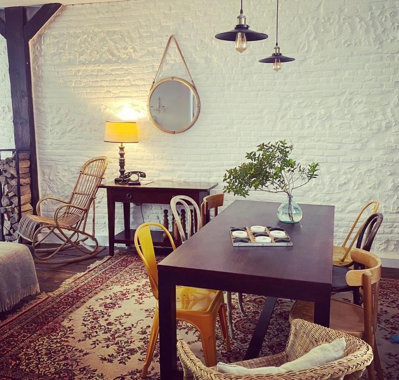 a dining room with a table and chairs and a mirror at charming guest house in Bolbec