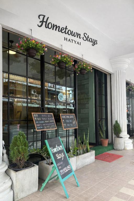 a building with two signs in front of it at Hometown Stays Hatyai in Hat Yai
