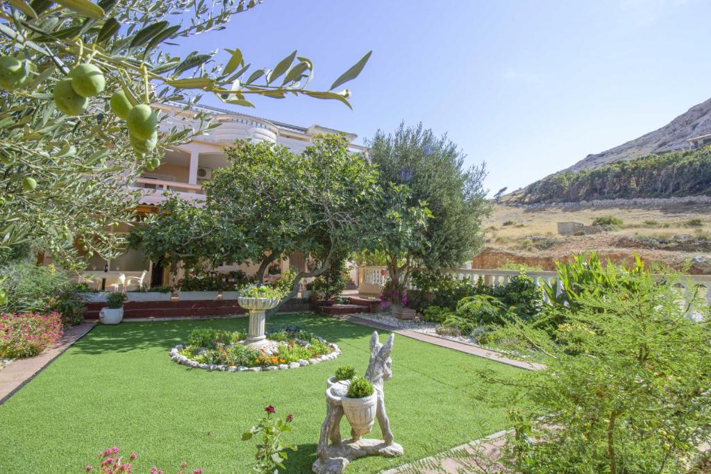 a garden in front of a house with trees and flowers at Sladana direct at the beach in Metajna