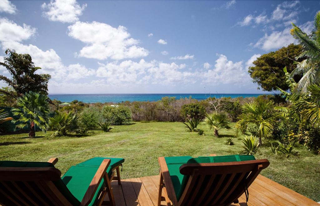 a patio with a table and chairs and the ocean at Gîte Pointe des Châteaux in Saint-François