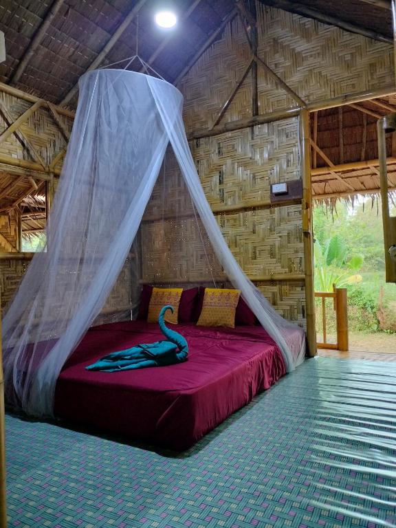 a bed in a room with a mosquito net at Kohmook Money RUEAN PHAI in Trang