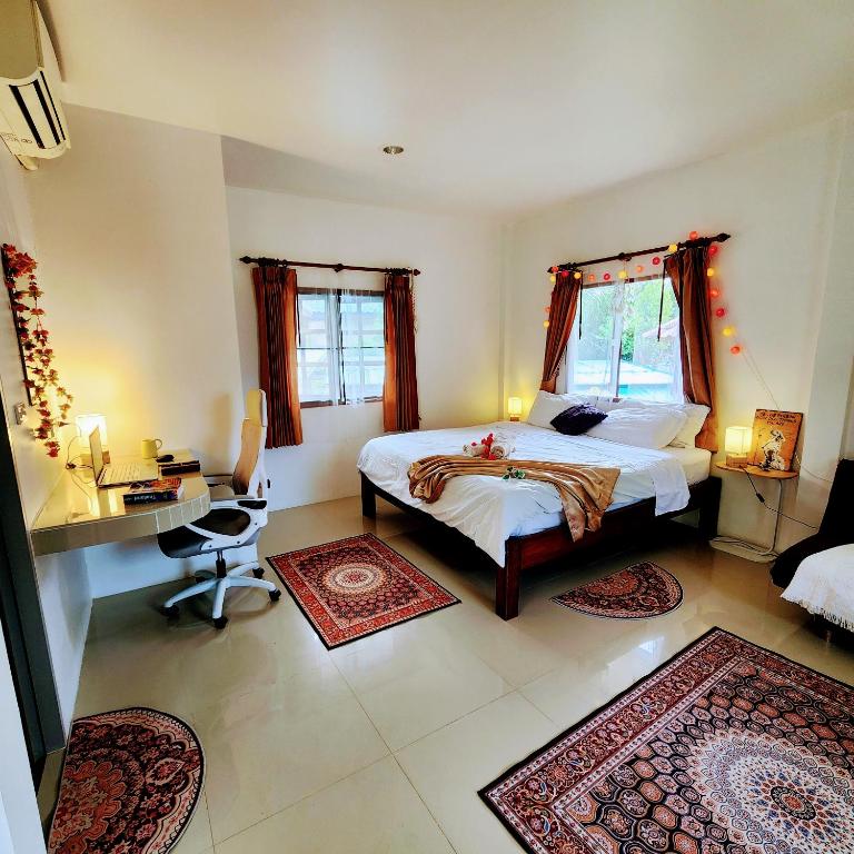 a bedroom with a bed and a desk and two windows at Beach Path in Haad Chao Phao