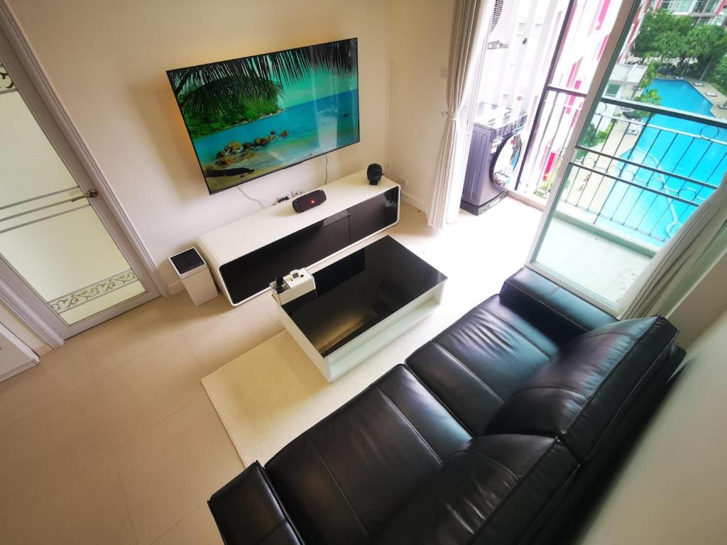 a living room with a leather couch and a television at Pattaya Pool View Condo in Nong Prue