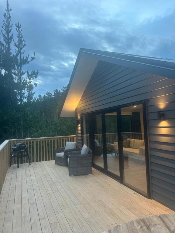 a deck with a couch and chairs on a house at Kauri Cabins Tranquil Retreat in Whitianga