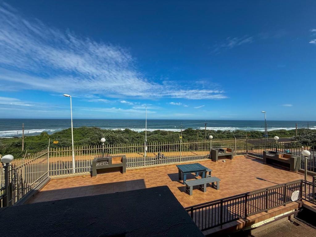 a balcony with benches and a table and the beach at 28 Breaker View 3-bedroom beach apartment in Durban