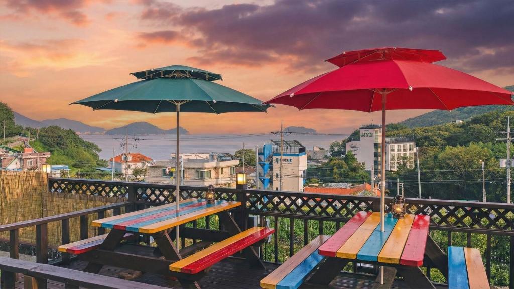 two picnic tables and umbrellas on a balcony at Geoje Araon Pension in Geoje