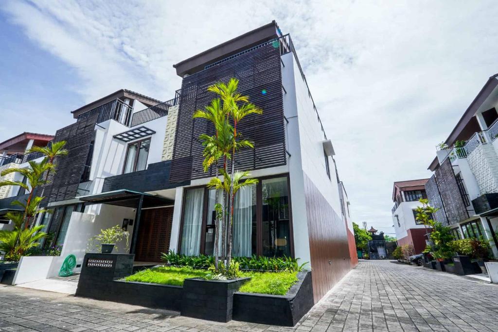 a building with palm trees in front of it at Norm Villa Kuta in Kuta