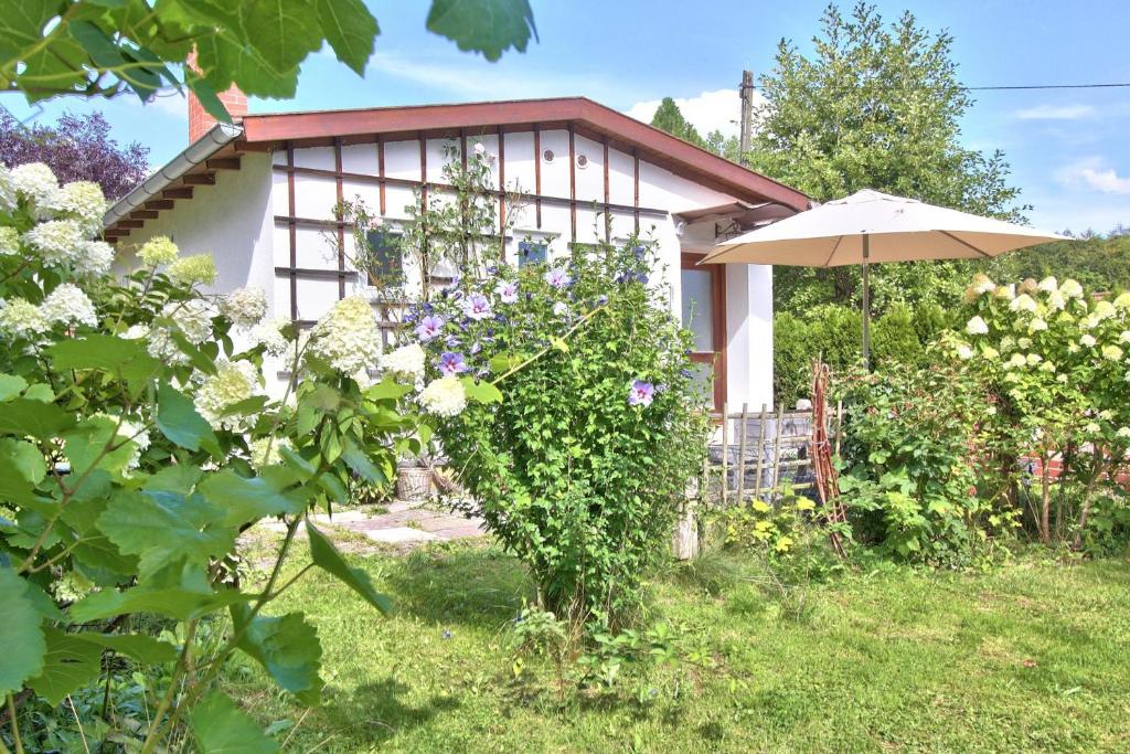 a small white house with an umbrella in a yard at Ferienhaus Schreieck in Pöcking