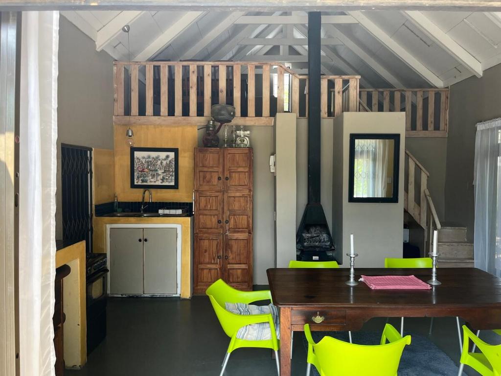 a dining room with a table and yellow chairs at Rapids View Cottage in Parys