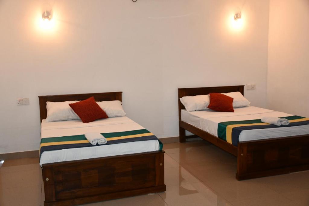 two beds sitting next to each other in a room at Ratnam Hotel Jaffna in Jaffna