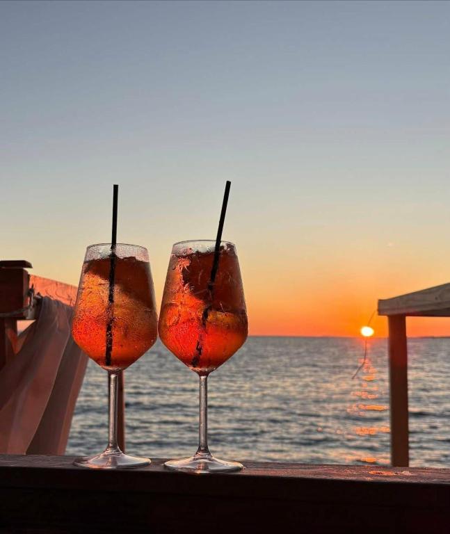 three wine glasses sitting on a table in front of the ocean at Azure Bay Resort in Sarandë