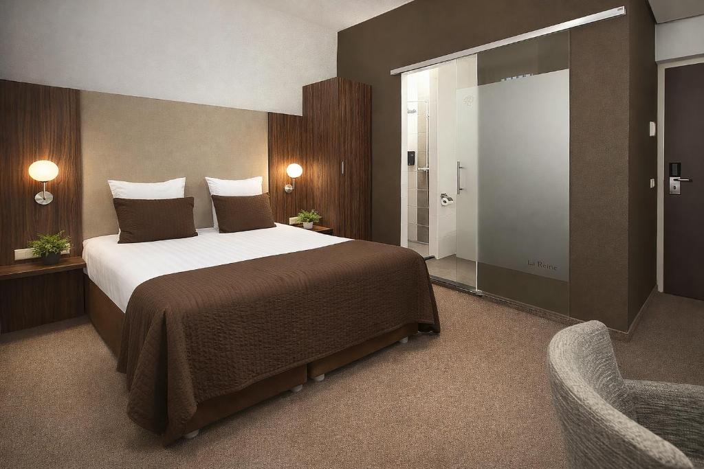 a bedroom with a large bed and a chair at Hotel La Reine in Eindhoven