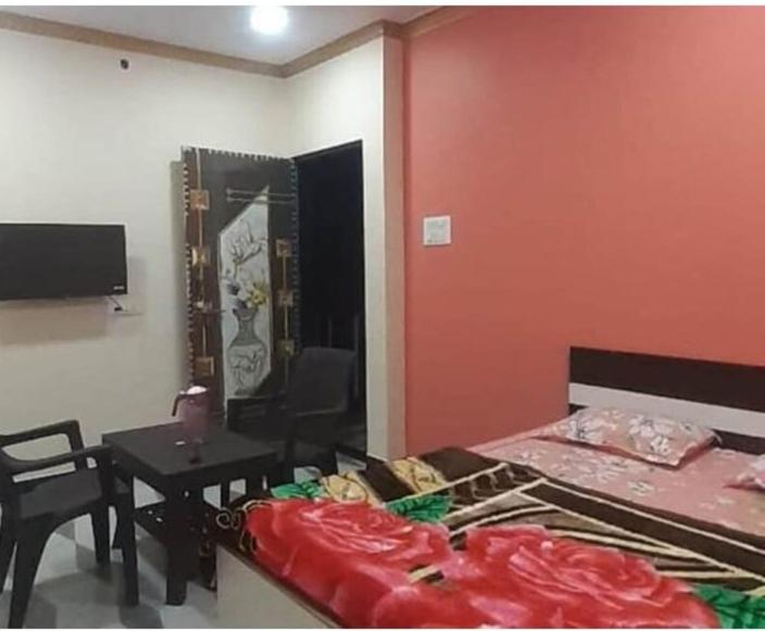 a bedroom with a bed and a table and a table and chair at Ganesh Cottage in Matheran