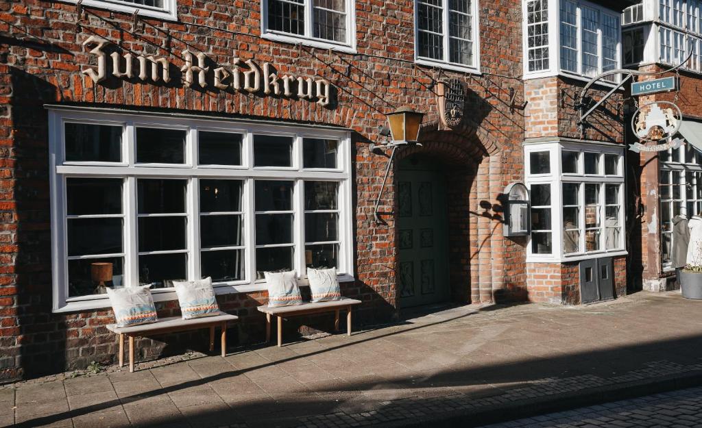 a brick building with benches in front of a store at Momento Heidkrug in Lüneburg