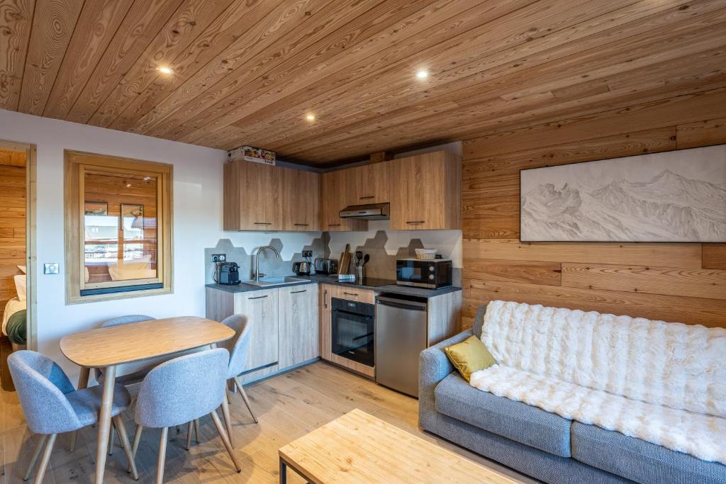 a living room with a couch and a table and a kitchen at Appartement Marmotte in Méribel