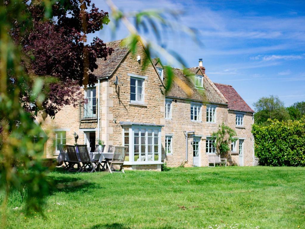 a large brick house with chairs in the yard at Corn Close in Stretton on Fosse