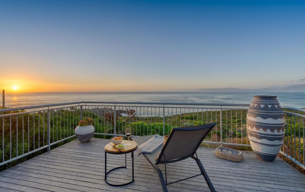 a deck with a view of the ocean at sunset at Walker Bay Villa in Gansbaai