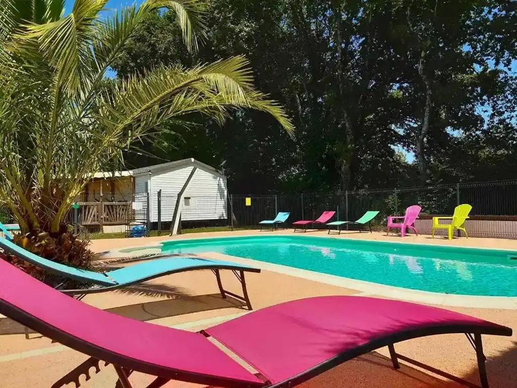 a swimming pool with pink and green lounge chairs next to it at ZEcamping 3 étoiles piscine chauffée toboggans pet friendly locatif TV 8 pers in Saucède