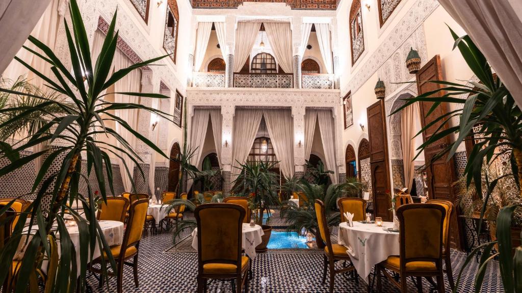 a restaurant with tables and chairs in a building at Riad Alassala Fes in Fez