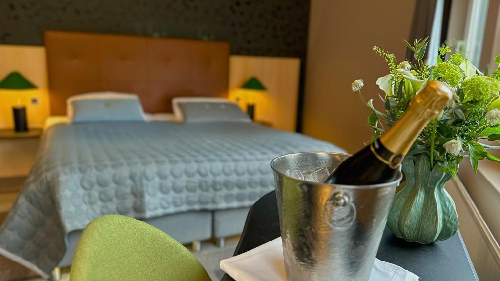 a bottle of champagne sitting on a table next to a bed at Hotel Lautrup Park in Ballerup