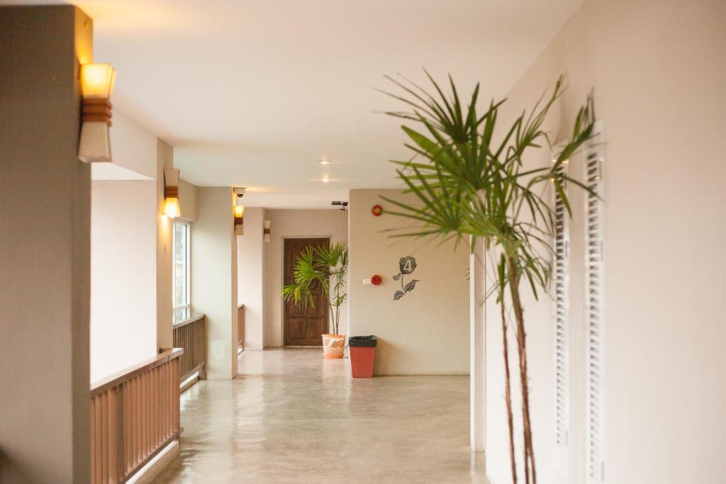 A bright hotel hallway with warm wall lights, plants, and a wooden railing.