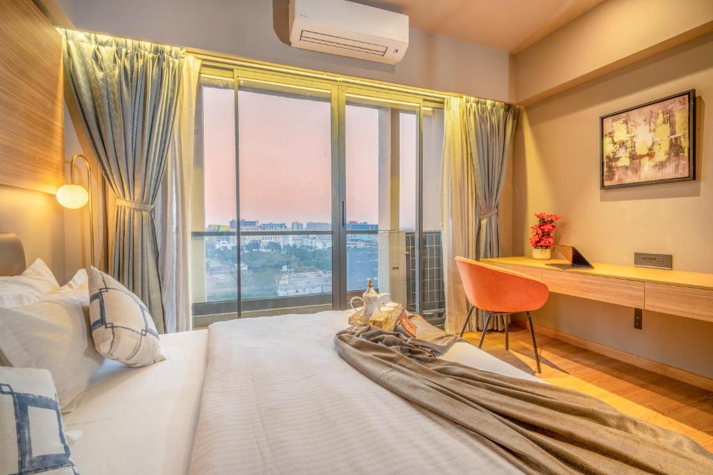 a bedroom with a bed and a desk and a window at The Vilton in Raipur